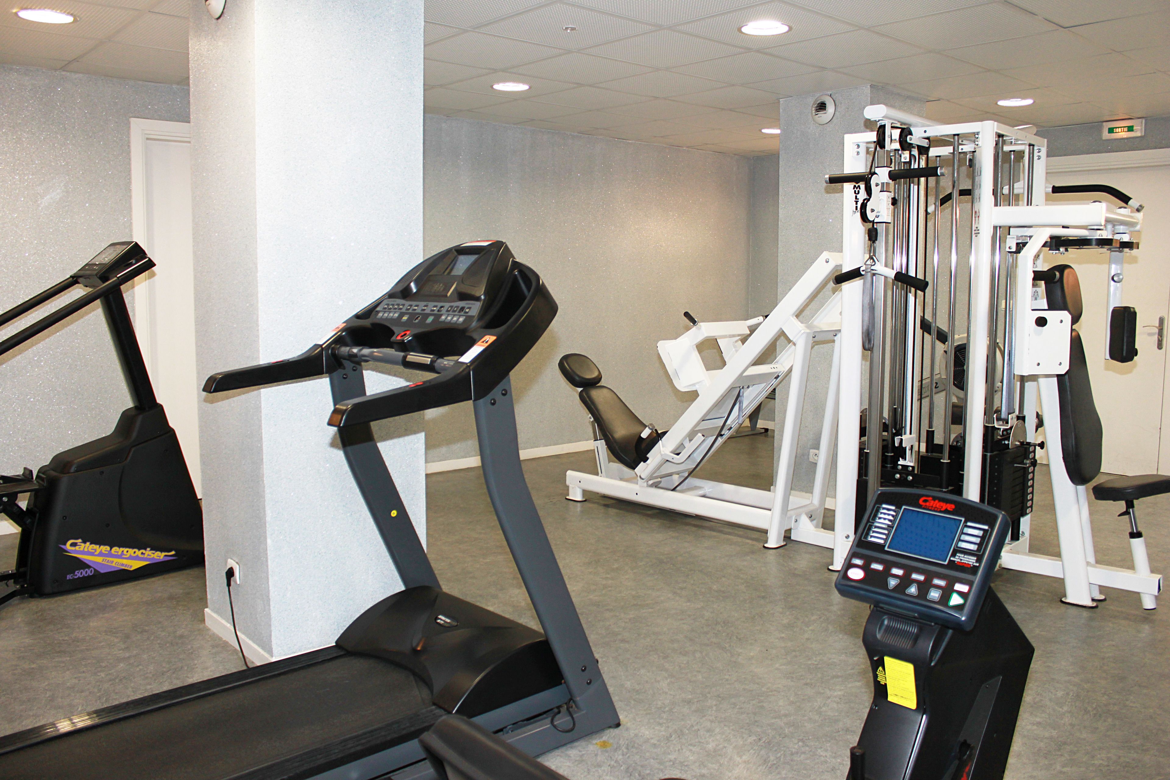 Un gimnasio con máquinas de cardio, equipo de entrenamiento de fuerza y un panel de control.