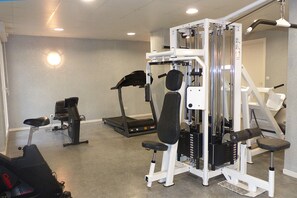 A gym with various exercise equipment including a treadmill, elliptical, and weight machines.
