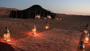 A desert campsite with tents and lanterns.
