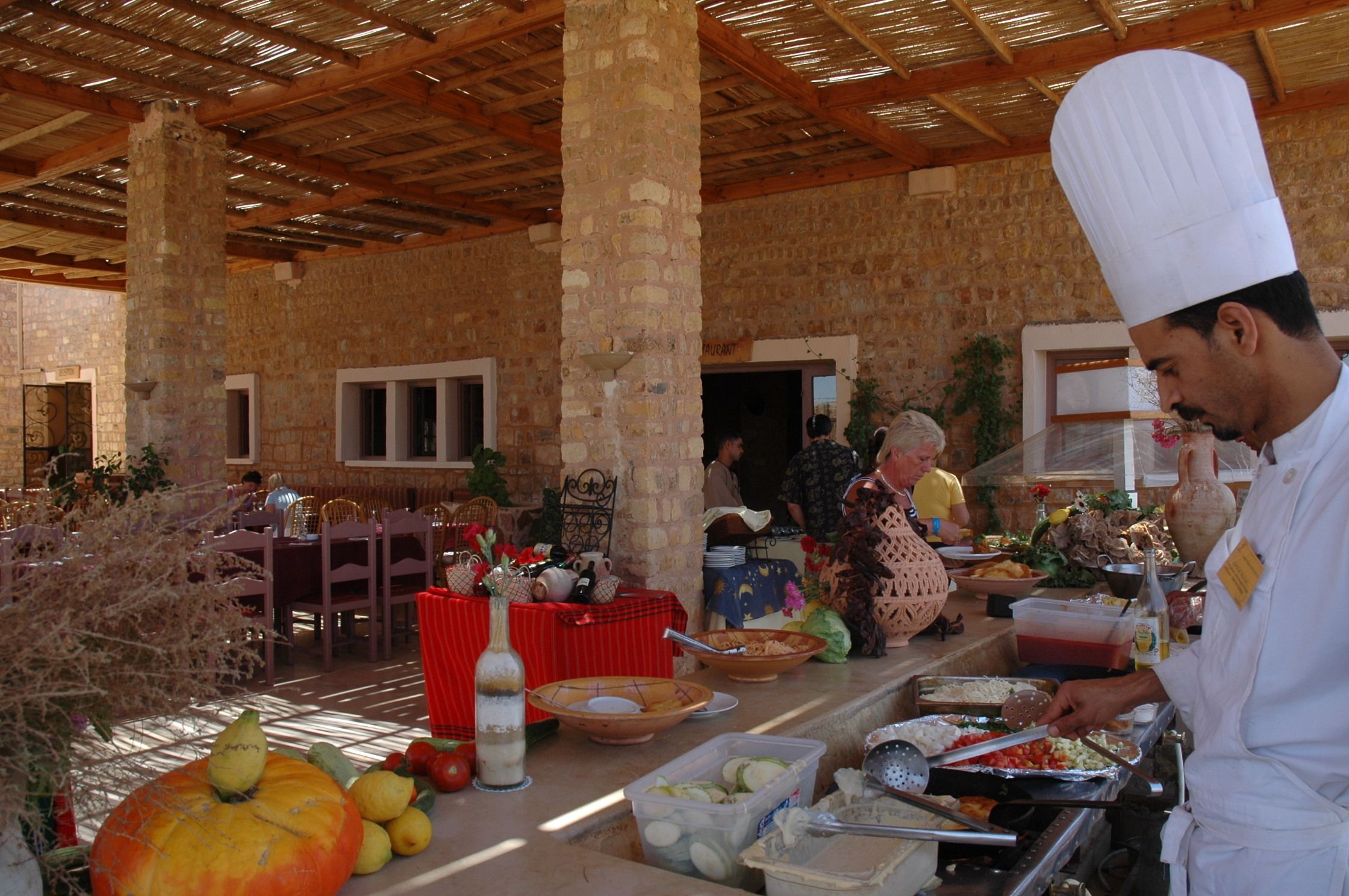 Un cocinero preparando comida en un edificio rústico de piedra con vigas de madera y paredes de ladrillo.
