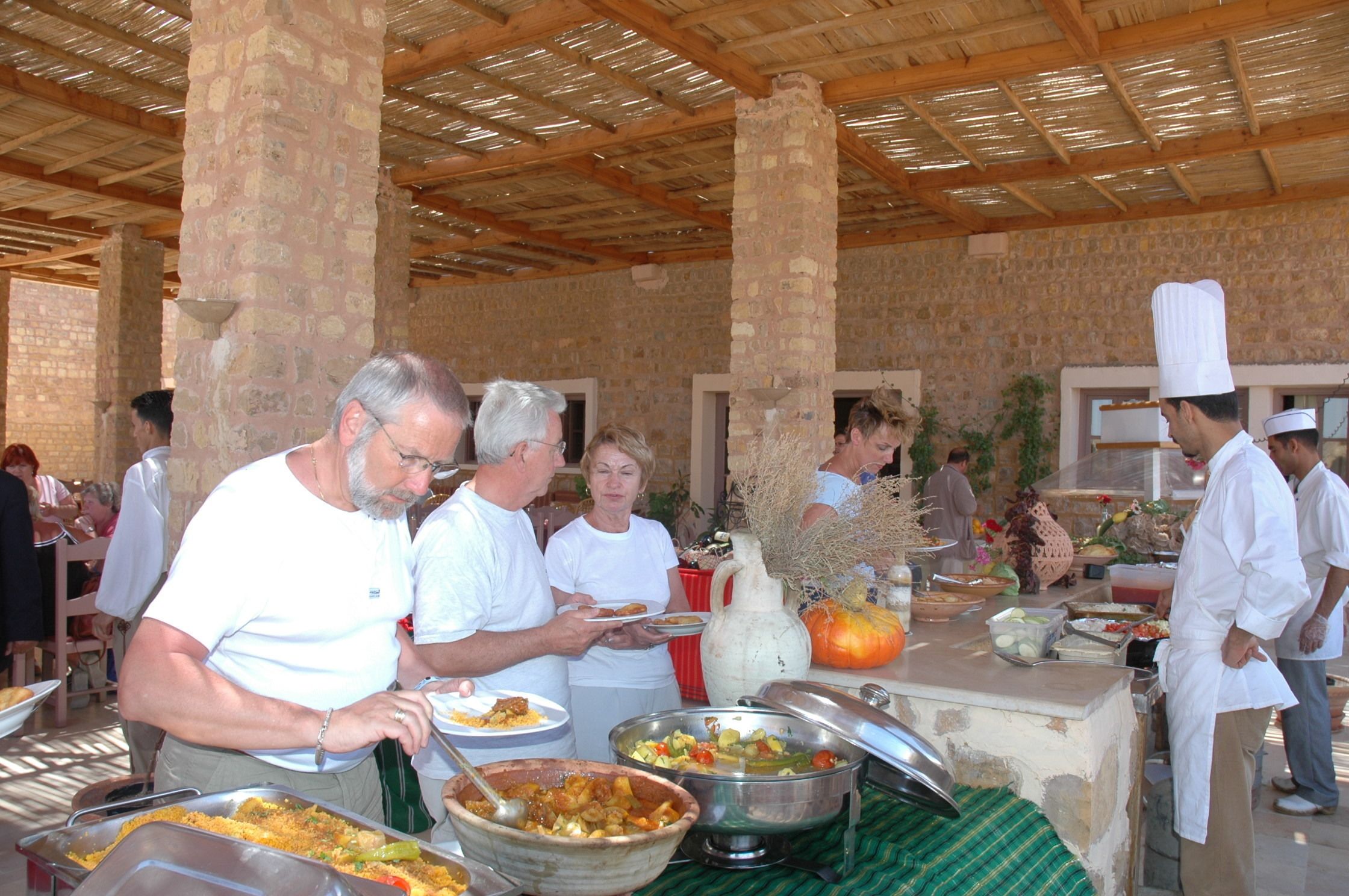 A buffet setup with various food items and a chef serving guests.