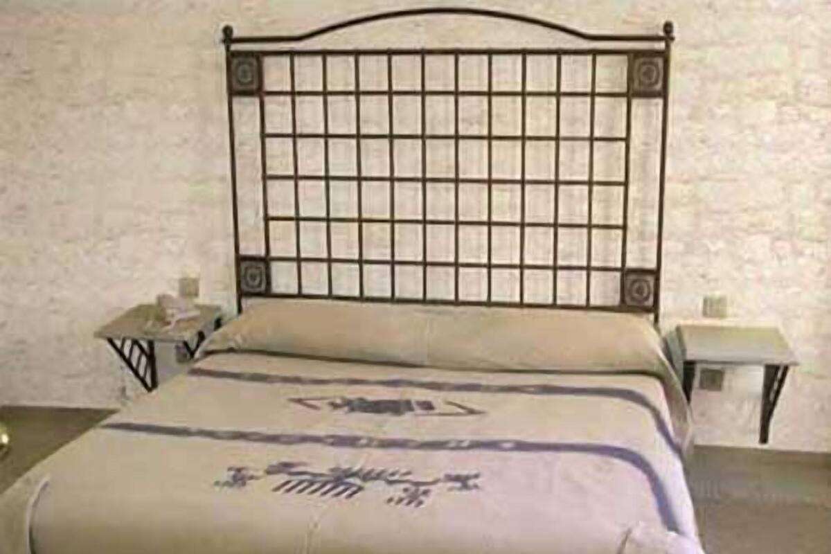 Een enkel bed met een metalen hoofdeinde en een eenvoudige spreidek.
