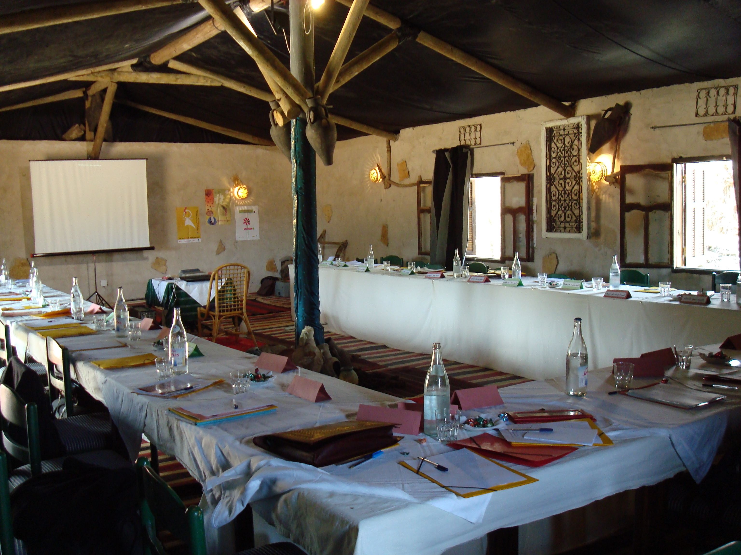 A conference room with a long table set for a meeting, equipped with nameplates, water bottles, and papers.