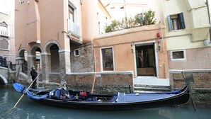 A gondola docked at a canal in Venice, with a building in the background. - Hotel Le Isole (Venice)