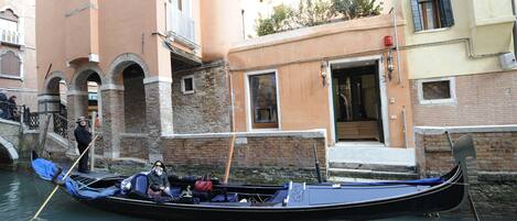 A gondola docked at a canal in Venice, with a building in the background.