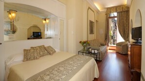 A hotel room with a large bed, a sofa, a TV, and a balcony with curtains. - Hotel Le Isole (Venice)