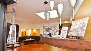 A reception area with a curved counter, hanging lamps, a map on the wall, and a certificate of excellence. - Hotel Le Isole (Venice)