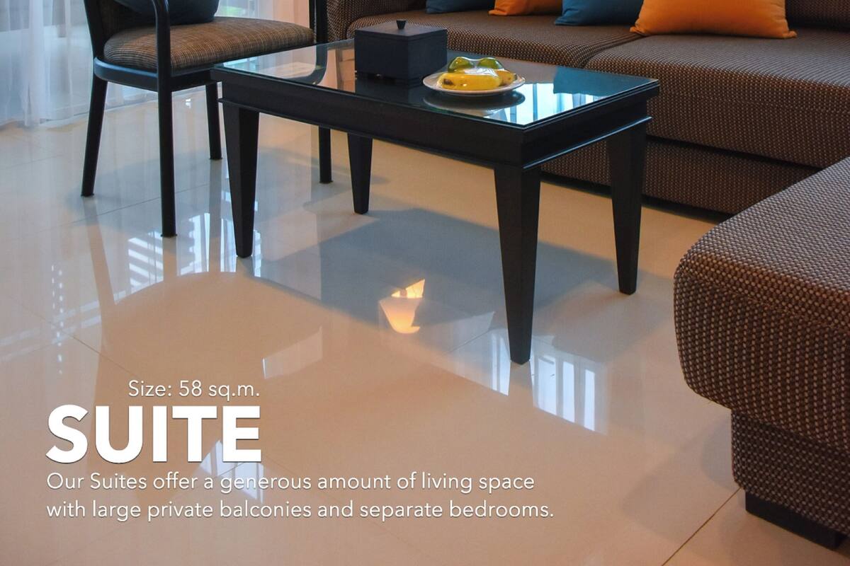 A suite with a large living area, a sofa with colorful cushions, a chair, a table, and a lamp. The suite has a size of 58 sq.m. and offers generous living space with large private balconies and separate bedrooms.