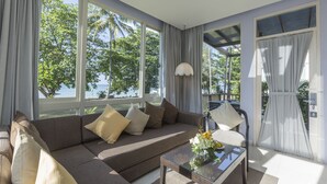 Un salon moderne avec un canapé, une table basse et de grandes fenêtres donnant sur l’extérieur.