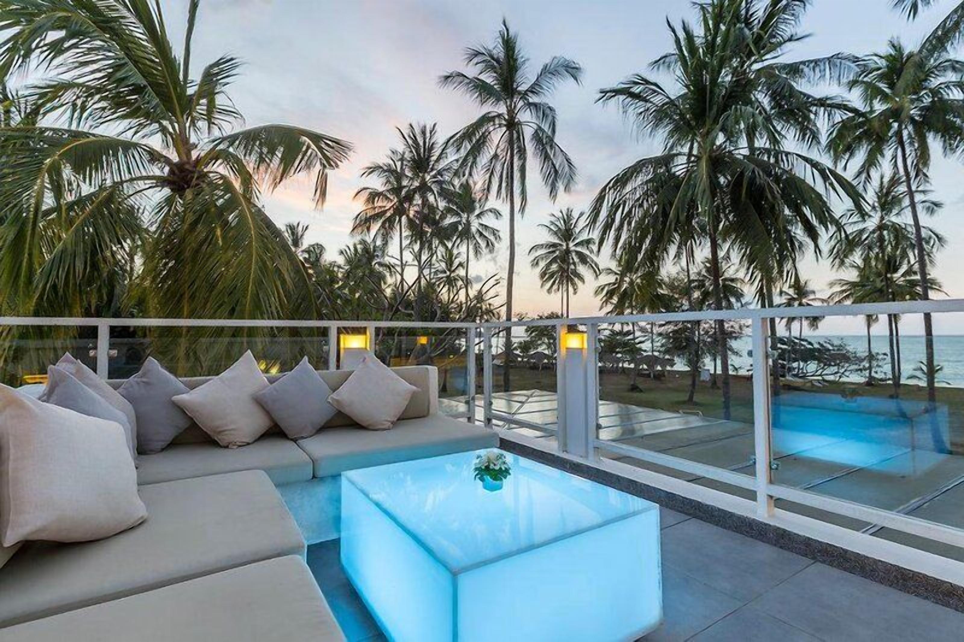A poolside area with a seating arrangement and a view of the ocean.
