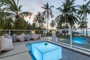 A poolside area with a seating arrangement and a view of the ocean.