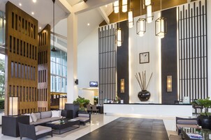 A modern lobby with a reception desk, seating area, and large windows.