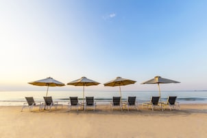 Playa privada, arena blanca, sillas reclinables de playa, sombrillas