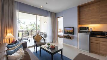 Una sala moderna con sofá, mesa de centro y televisor. Hay una zona de cocina con microondas y refrigerador.