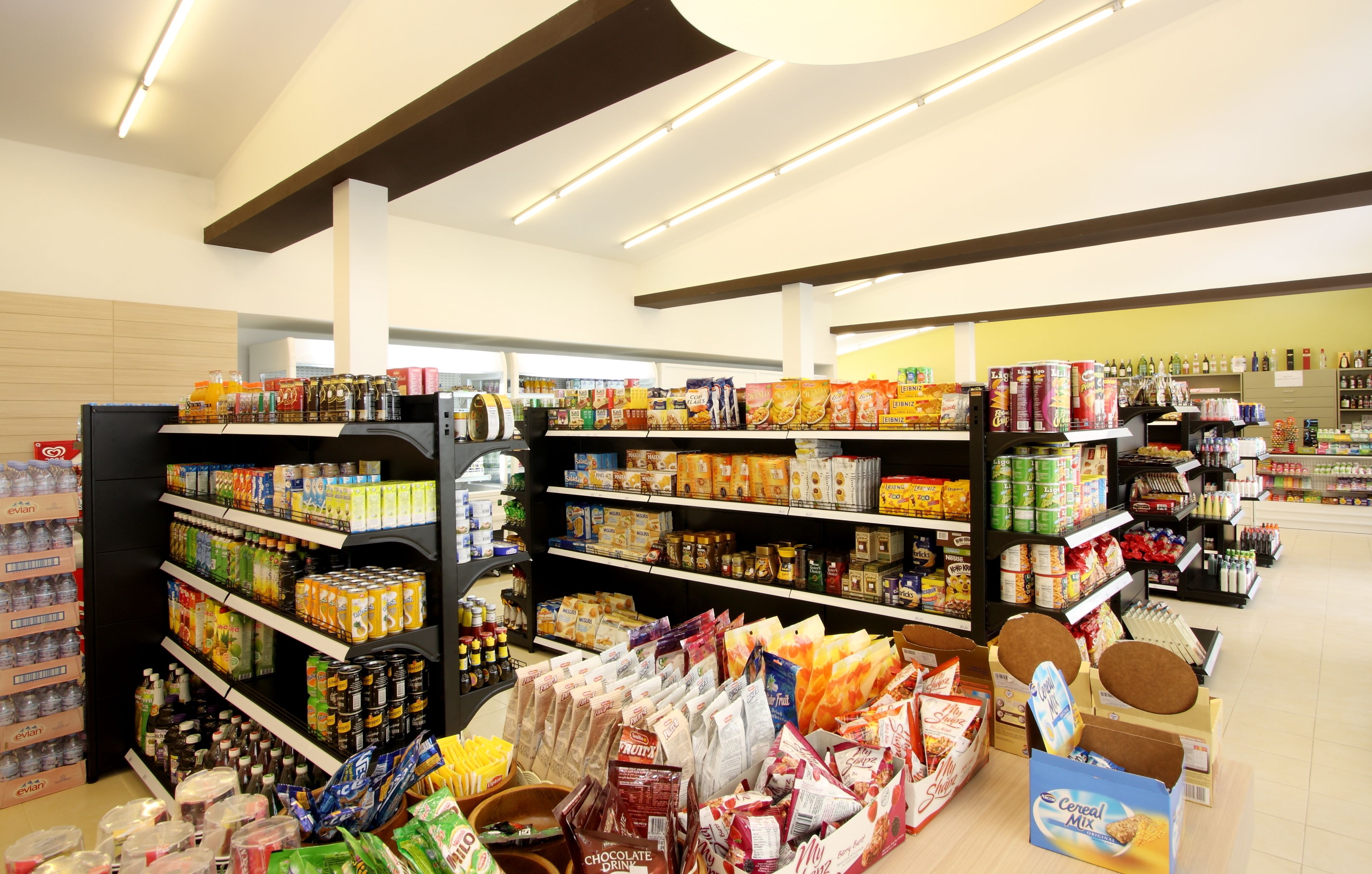 A grocery store interior with shelves stocked with various food items and beverages.