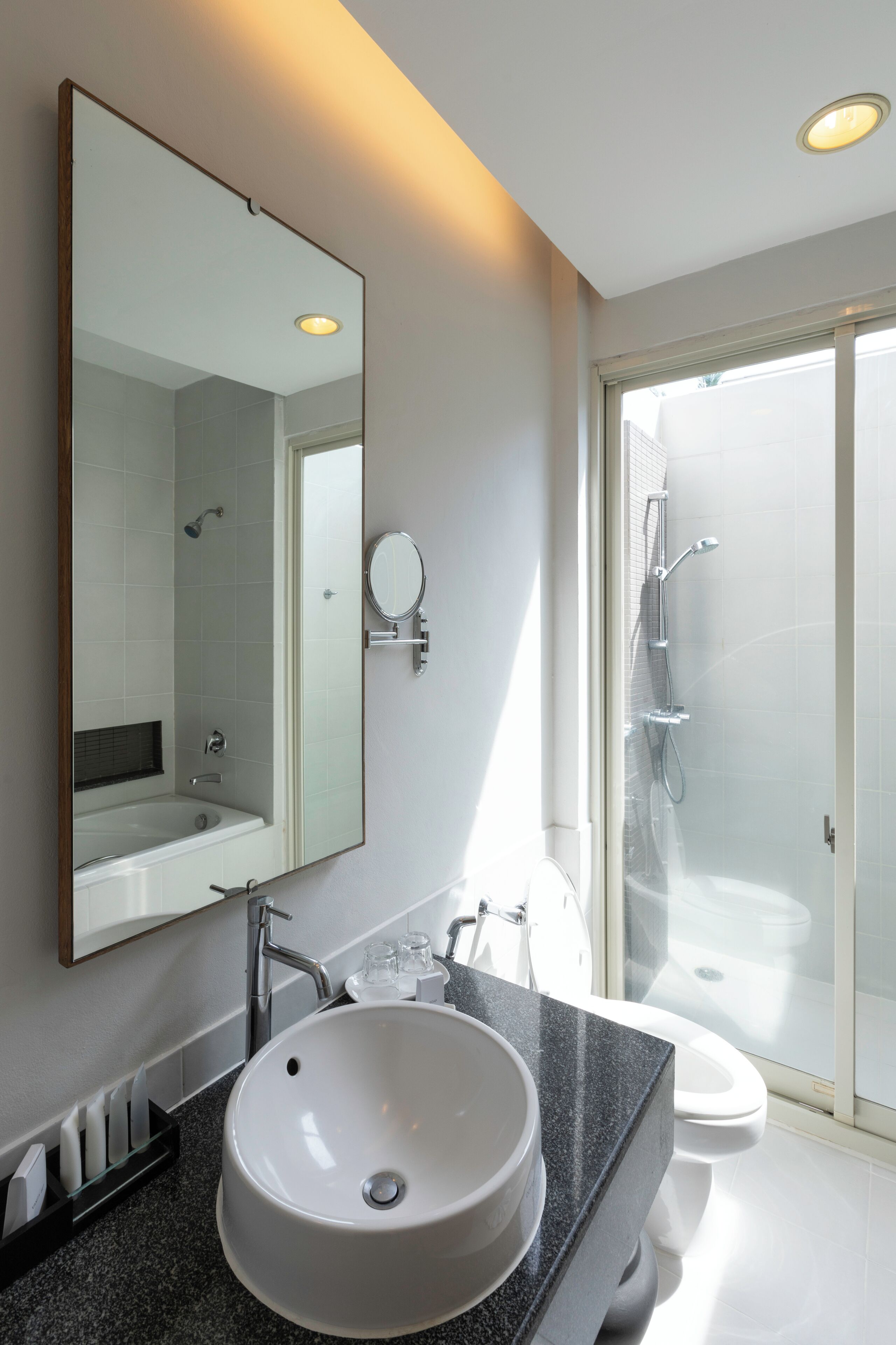 Un baño moderno con un espejo grande, un lavamanos y una ducha.