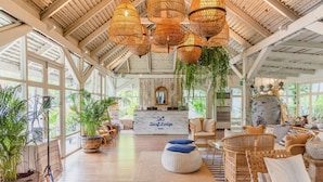 A spacious lobby with wooden floors, wicker furniture, and hanging wicker lamps. - The Peri Hotel Hua Hin (Hua Hin)