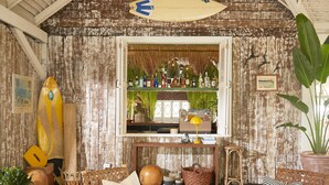 A rustic bar area with wooden walls, a surfboard, and a variety of bottles. - The Peri Hotel Hua Hin (Hua Hin)