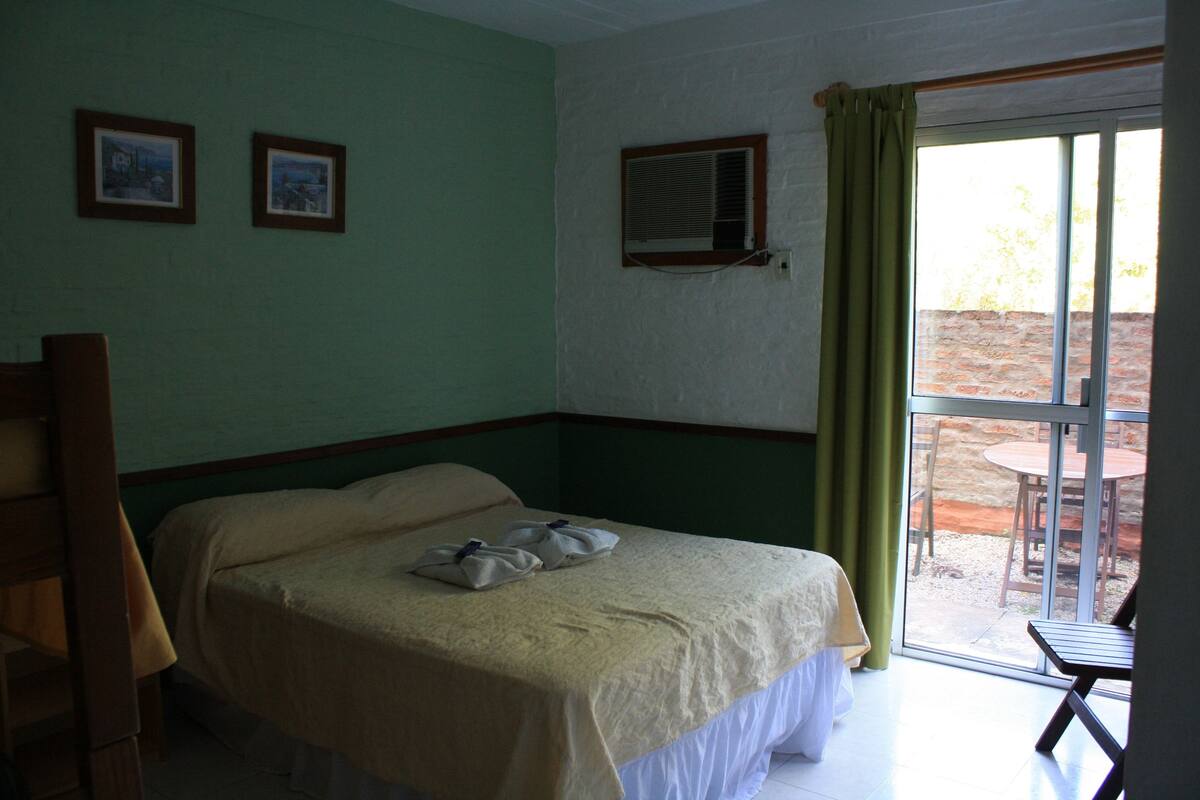 A room with a bed, a window with a curtain, and a wall-mounted air conditioner.