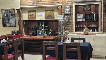 Un restaurante acogedor con paredes de ladrillo, muebles de madera y una cocina visible al fondo.
