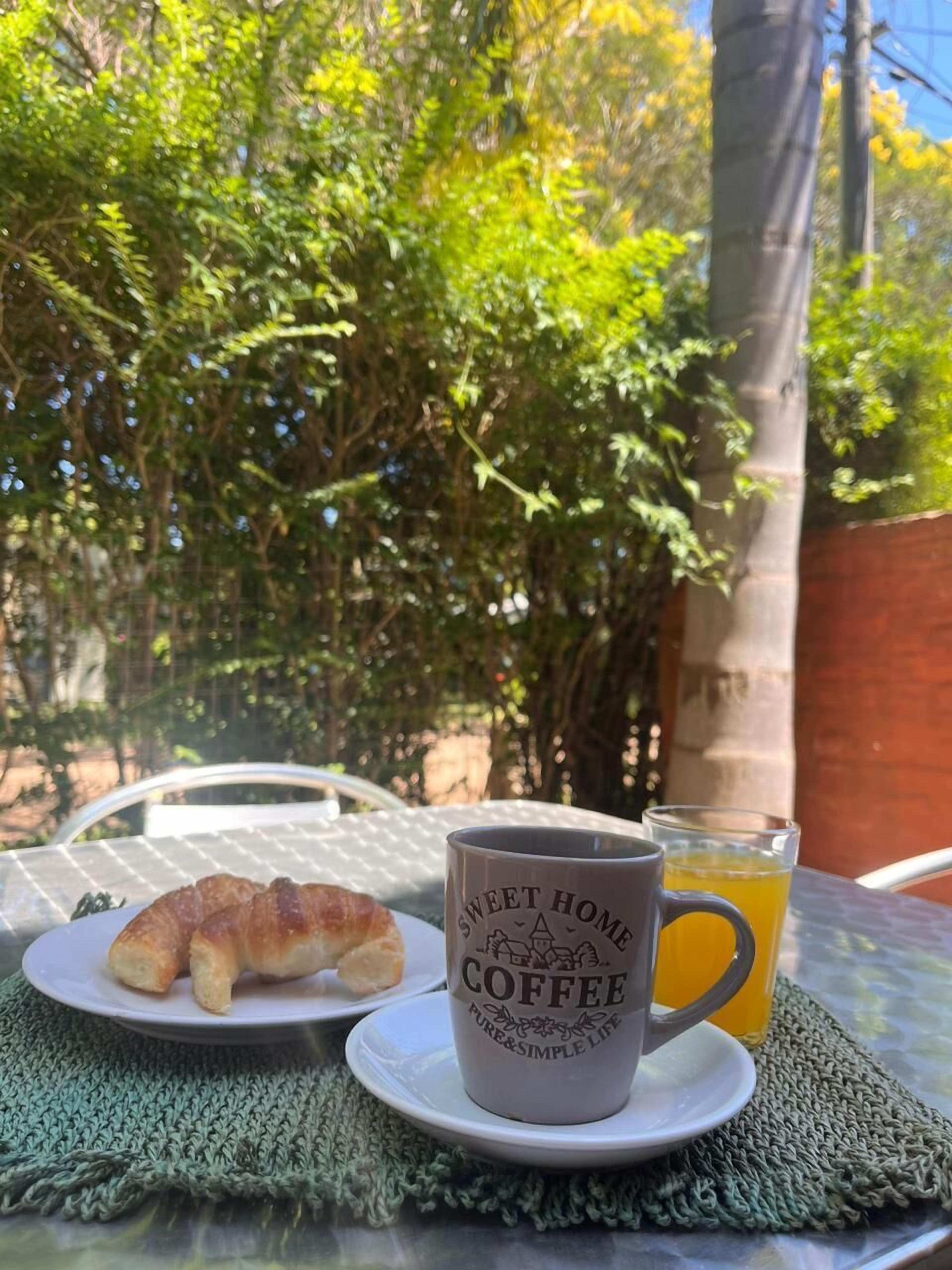 Uma mesa com um prato de croissants, uma caneca com a inscrição 