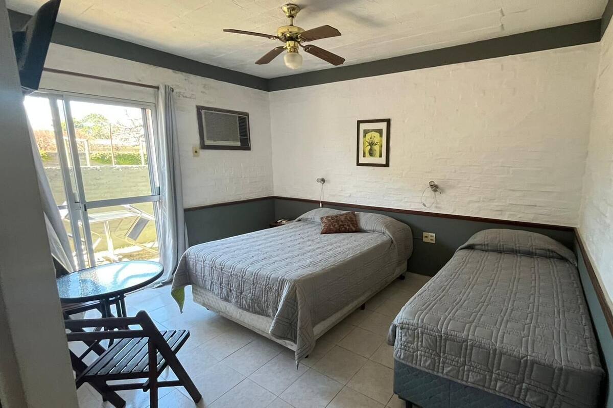 Une chambre avec deux lits, une petite table et un ventilateur de plafond.