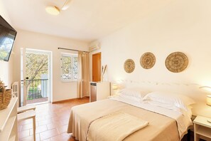 Un dormitorio con cama, mesitas de noche, televisor, ventana con cortinas y puerta al exterior.