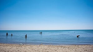 A beach with people in the water and a clear sky.