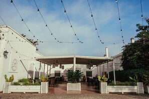 Un patio al aire libre con barandillas blancas, luces colgantes y plantas en macetas.