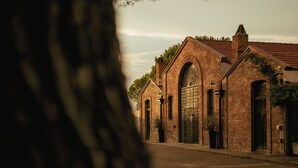 A brick building with a large arched entrance and a smaller door, surrounded by a street.