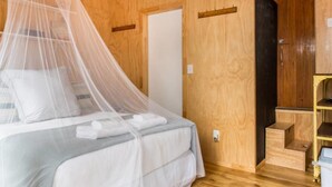 Une pièce en bois avec un lit, une armoire et une petite étagère en bois.
