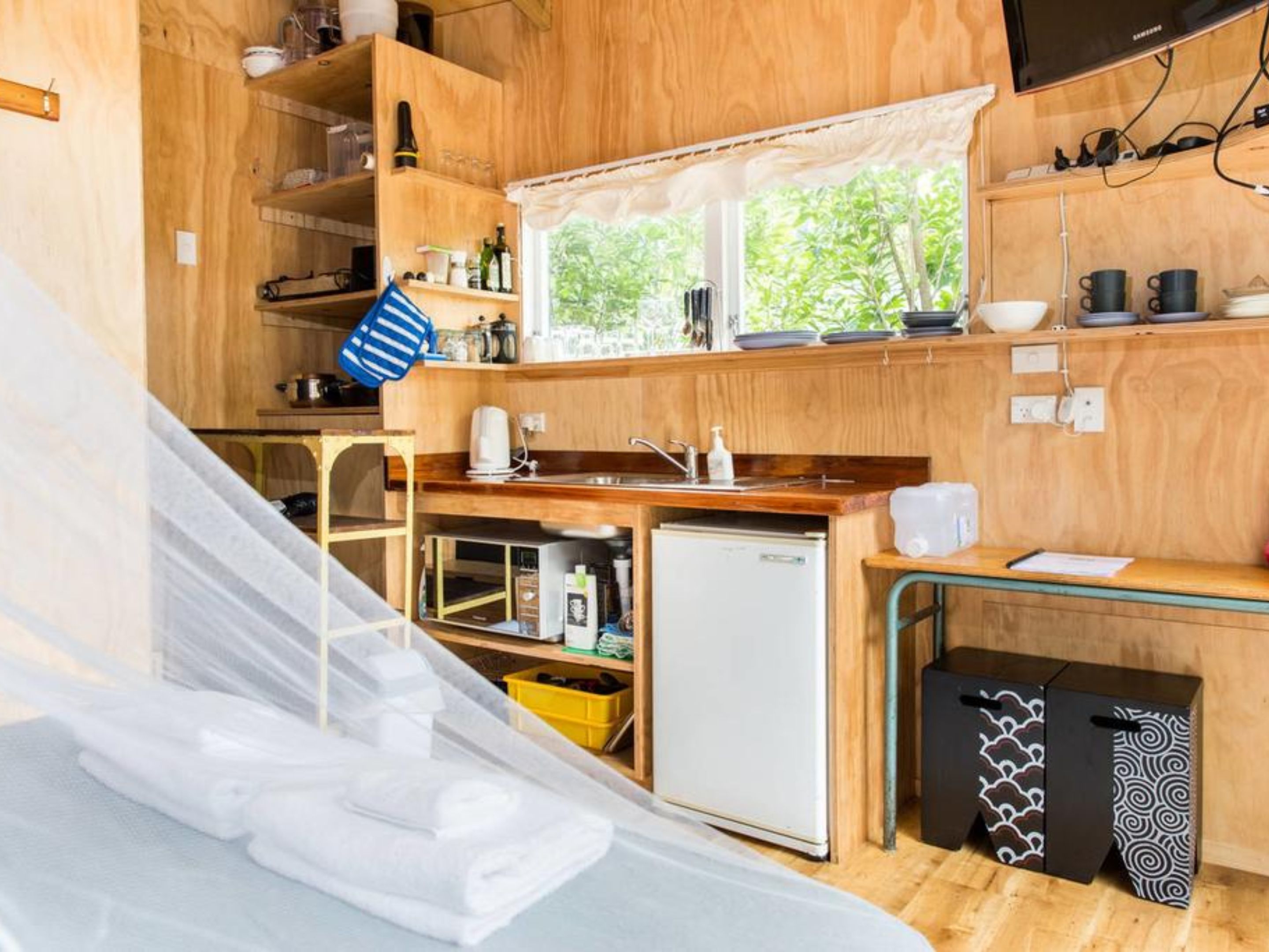 A compact kitchen with wooden cabinets, a sink, a microwave, and a refrigerator.