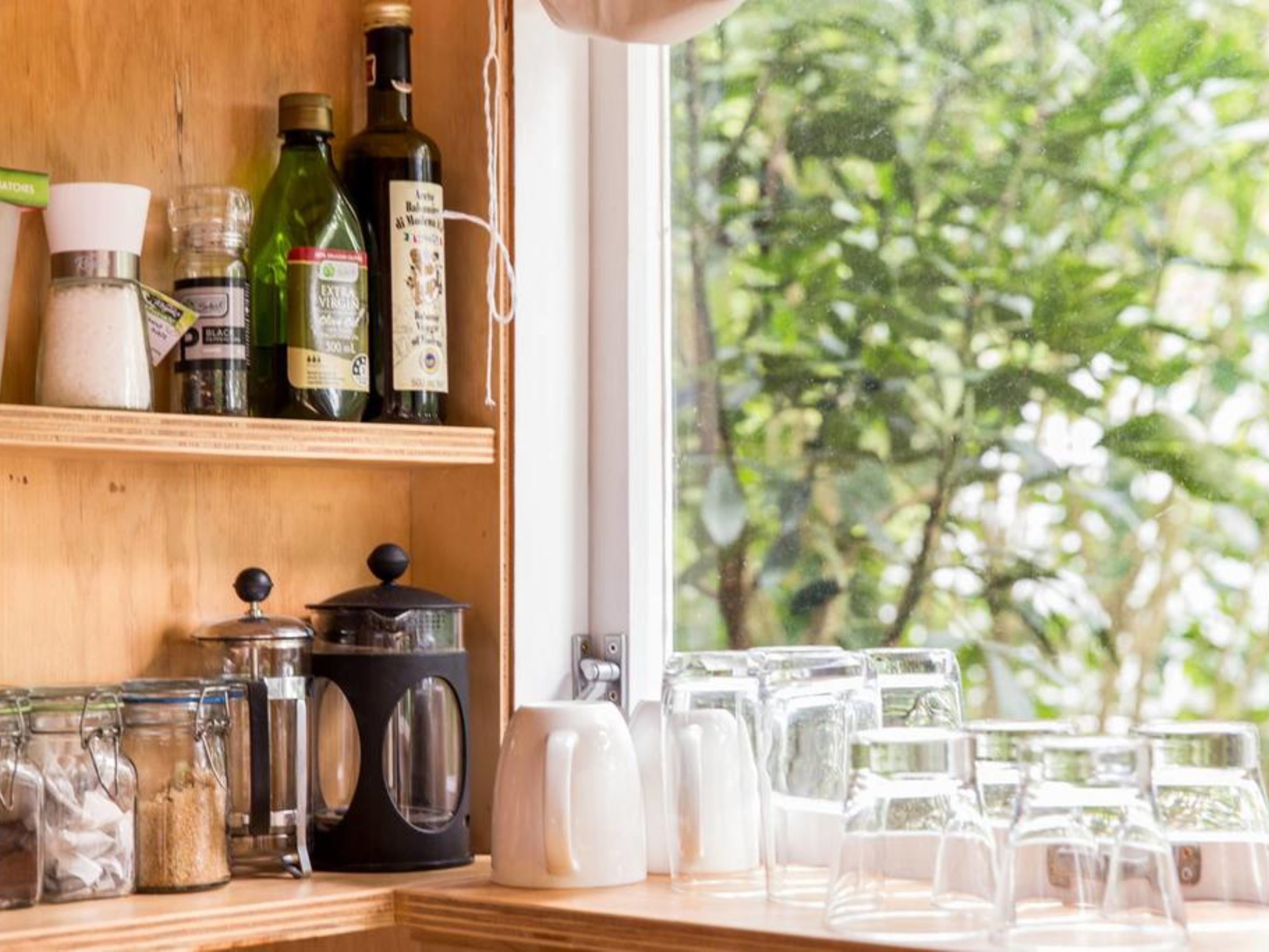 A kitchen counter with various kitchen items, including jars, a coffee maker, and glassware.