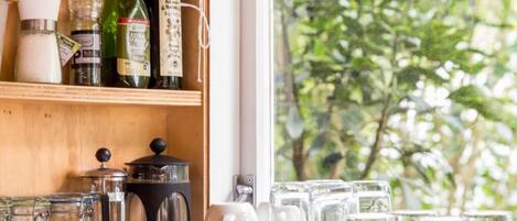 A kitchen counter with various kitchen items, including jars, a coffee maker, and glassware.