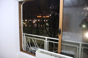 A window with a view of a park at night, including trees and distant lights. - Guesthouse Anja (Skopje)