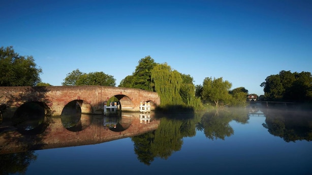 A calm river with a bridge featuring three arches and a small boat docked at the center. - The Great House, Sonning, Berkshire (Reading)