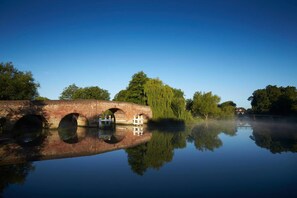 A calm river with a bridge featuring three arches and a small boat docked at the center. - The Great House, Sonning, Berkshire (Reading)