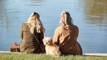 Zwei Personen sitzen am Wasser auf der Wiese.
