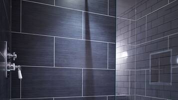 Une douche moderne avec des carreaux foncés et une paroi en verre.
