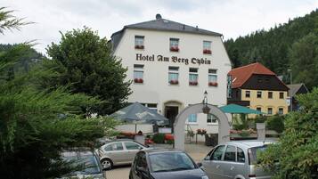 Un bâtiment portant l’inscription « Hôtel Am Berg Cubin », avec un espace de stationnement devant.