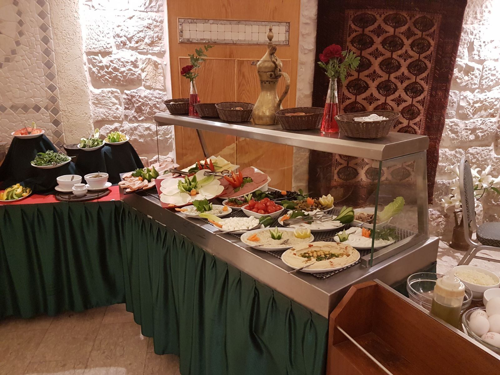 A buffet with various dishes, a vase with flowers, and a decorative pitcher on a table.