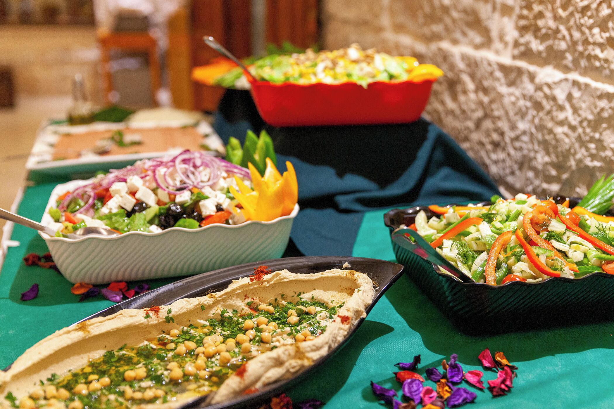 A table with various dishes including a salad, a dish with red onions, and a dish with chickpeas.