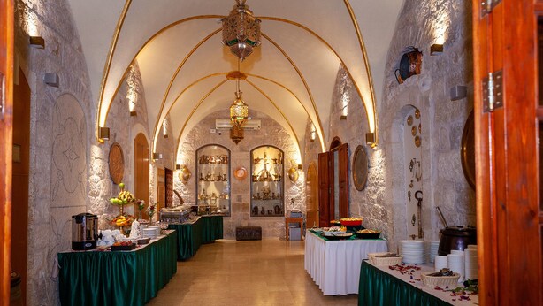 A banquet hall with tables set for a meal, featuring stone walls and arched ceilings. - Azzahra Boutique Hotel & Restaurant - Jerusalem (Jerusalem)