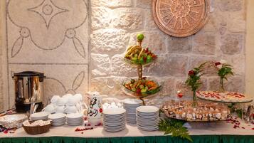 A buffet table with various food items, plates, and a decorative wall.