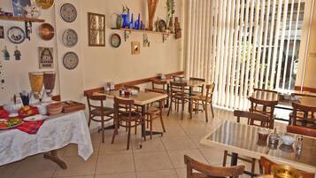 A dining area with multiple tables and chairs, a white tablecloth-covered table, and decorative plates on the walls.