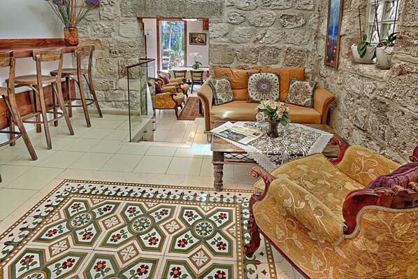 A cozy living room with a stone wall, a sofa, a coffee table, and a patterned rug.