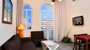 A room with a sofa, a table, a chair, and a window with curtains.