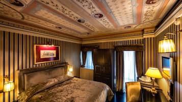Ein Hotelzimmer mit einem großen Bett, einem Schreibtisch mit Lampe, einem Fernseher und einem gerahmten Bild an der Wand.