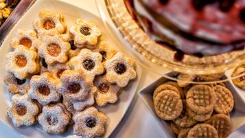 Un plato de galletas con forma de estrella y relleno, un plato de galletas redondas y un plato decorativo con una composición de frutas.