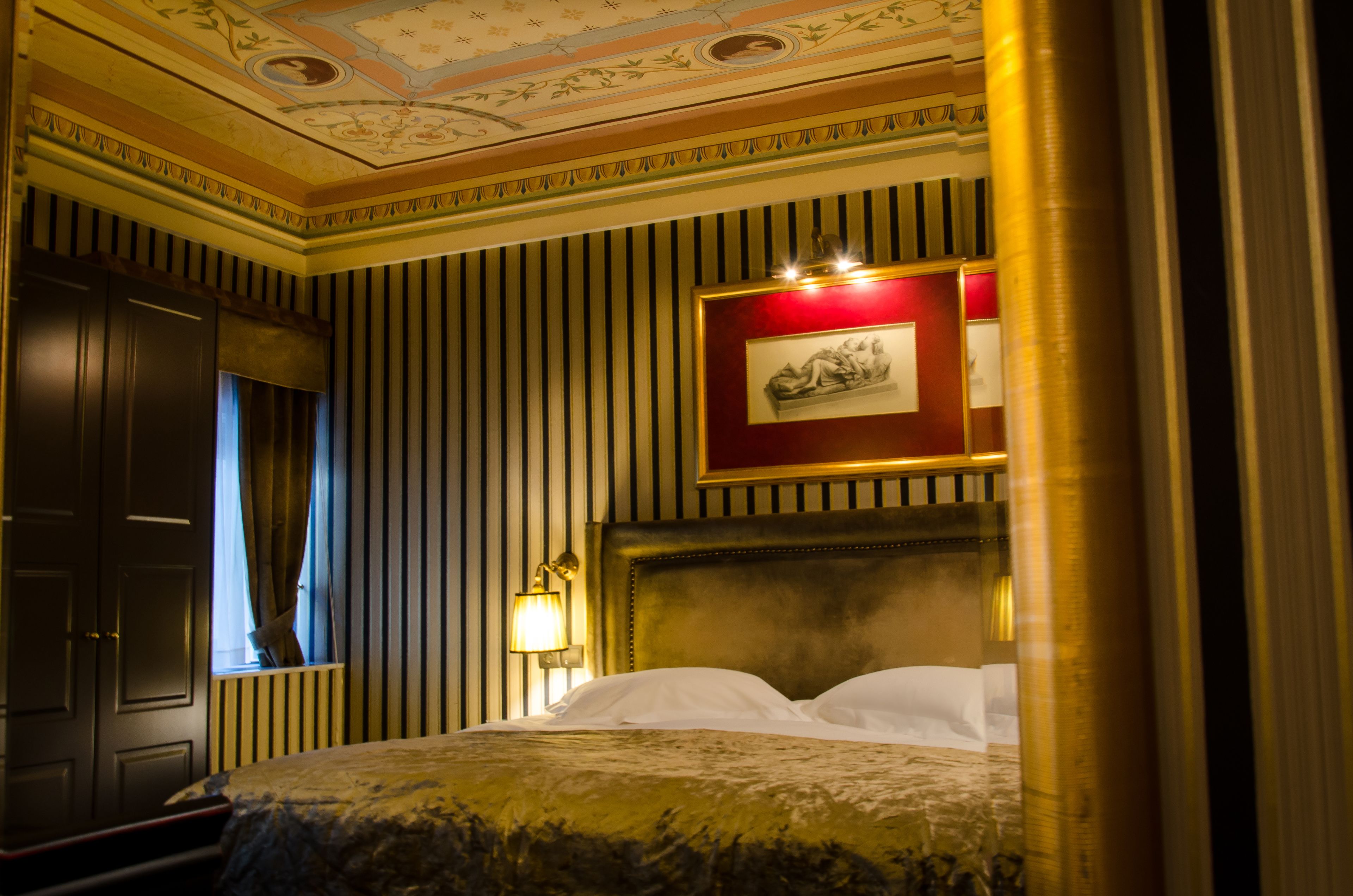 Une chambre d’hôtel avec un grand lit, une œuvre d’art encadrée au mur et un plafond décoratif.